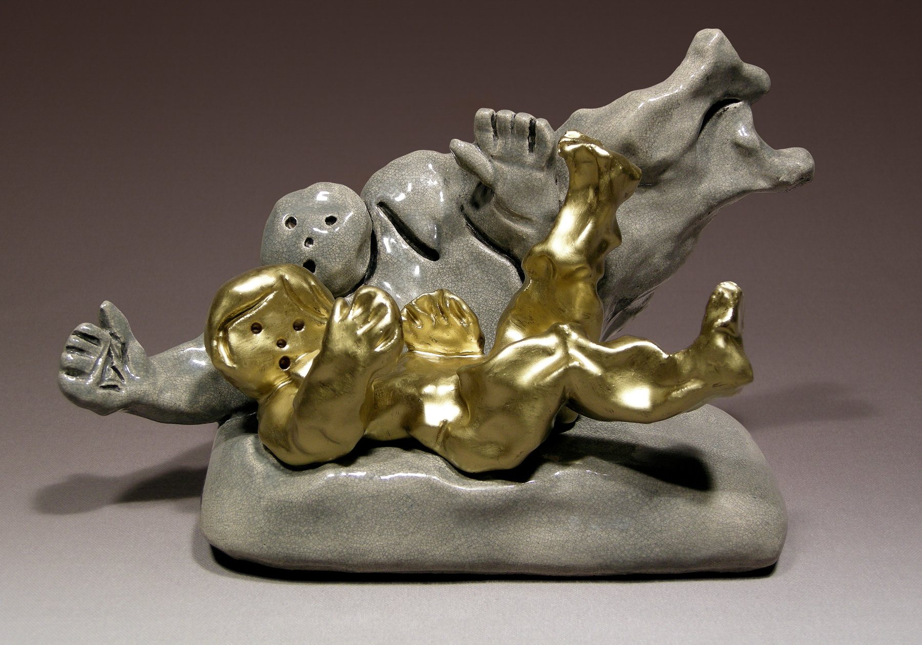 Reclining elephant embracing gilded figures, in glazed stoneware