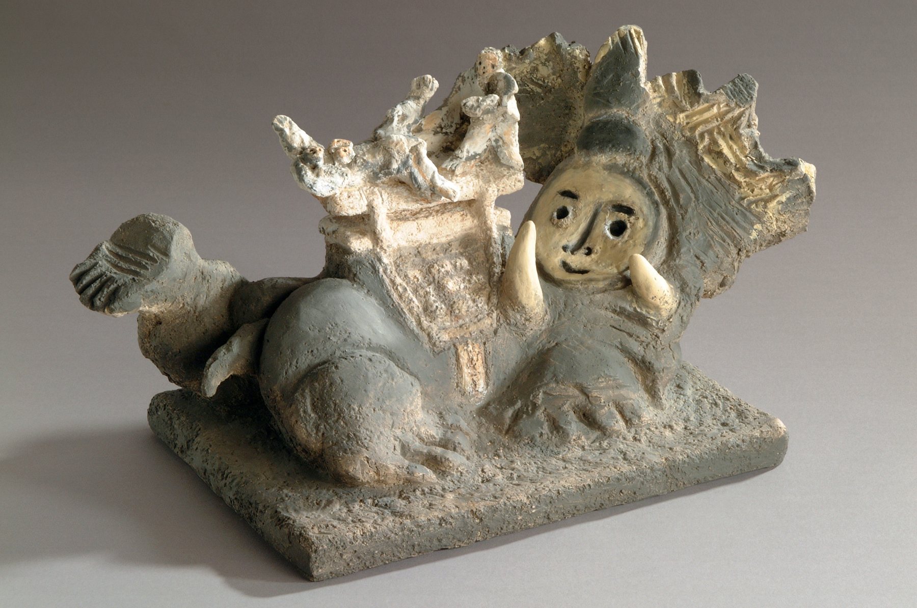 Reclining figure holding its face beneath a golden elephant, in terracotta