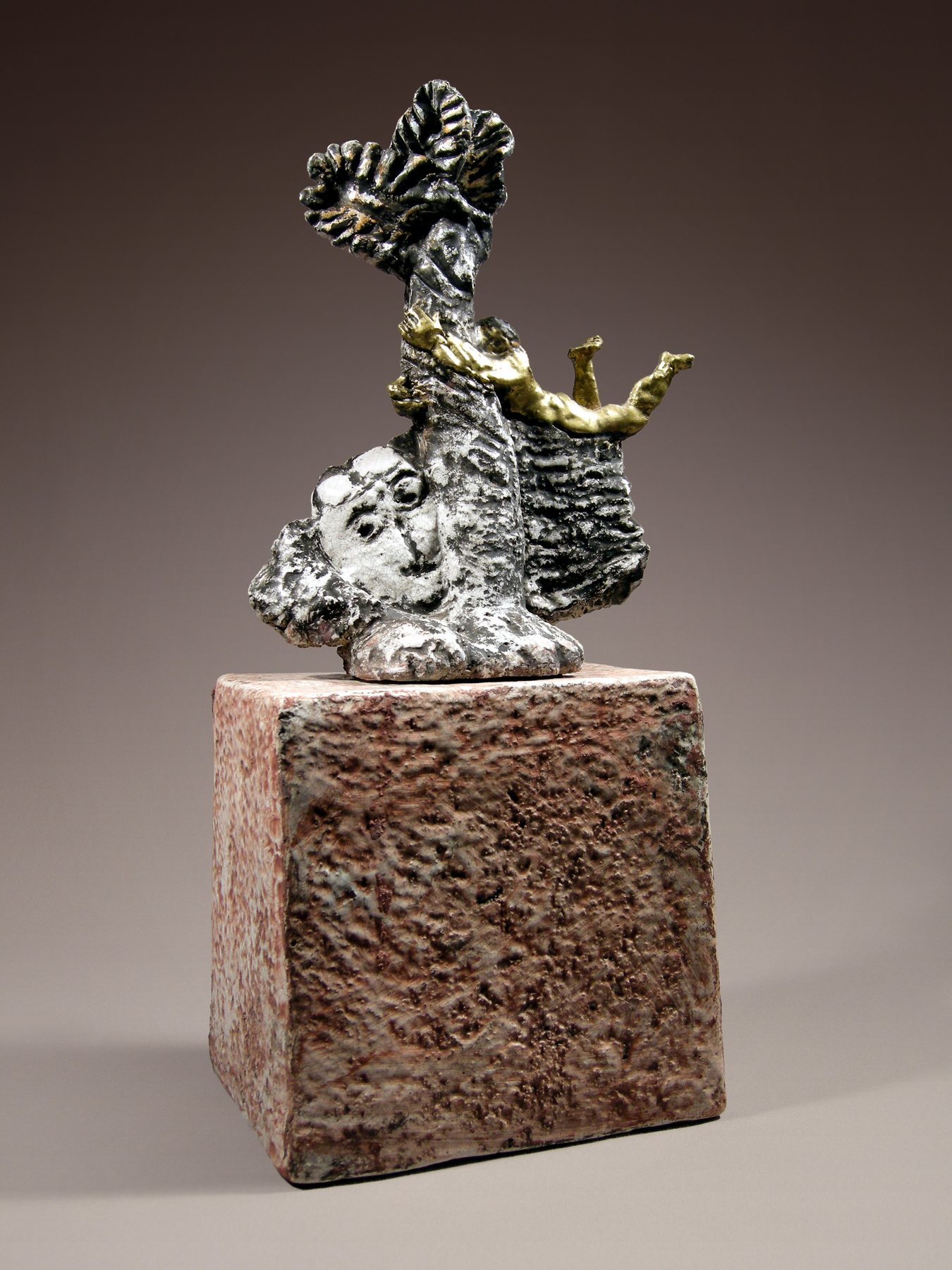 Winged gilded figure balancing on an elephant’s head, above a pinkish stone cube