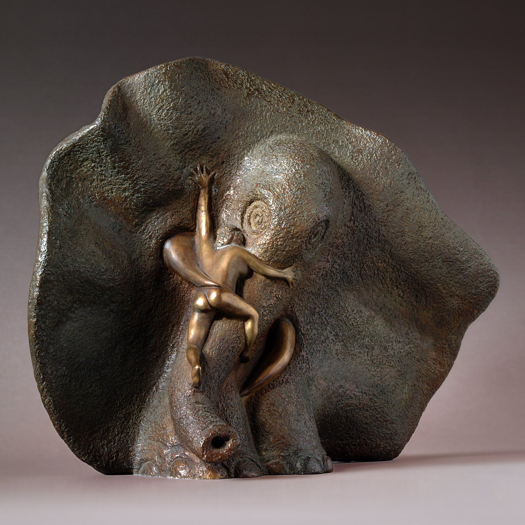 A small golden figure climbs the head of a large bronze elephant