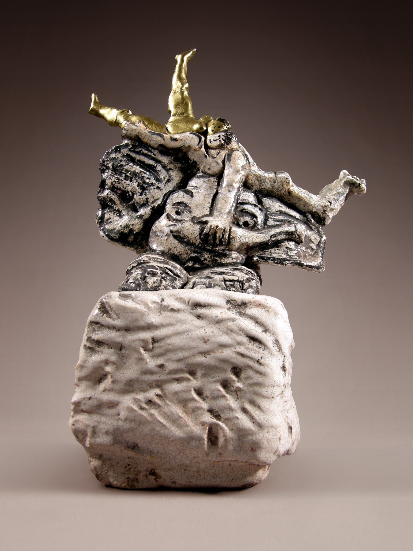 Glazed stoneware elephant rolling on a stone block, a gilded figure on its back