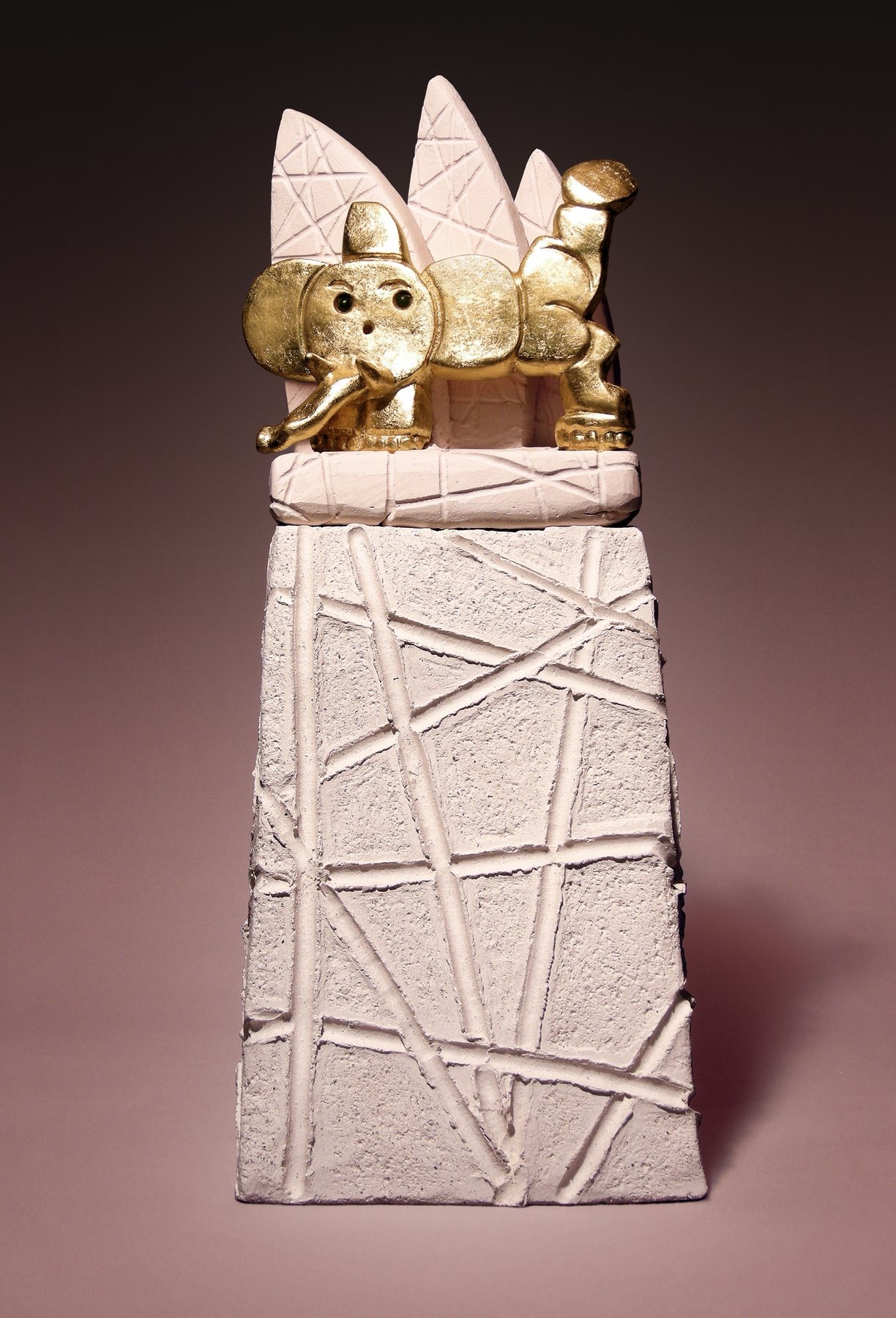 Small golden elephant lying among white leaves, on an incised plinth